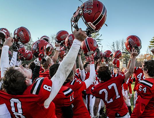 Groupe of Football players celebrating raising their helmets